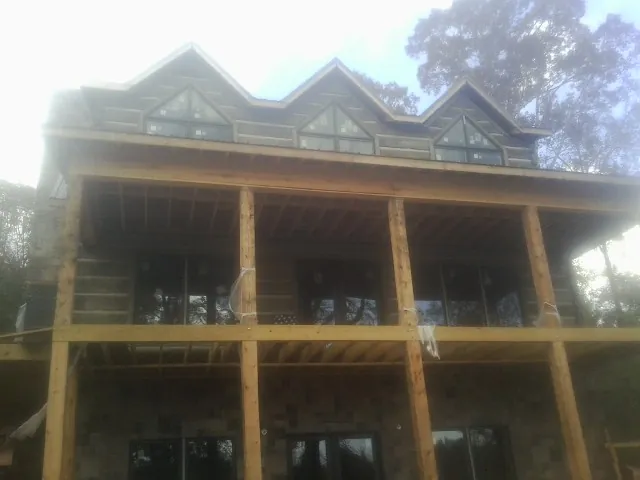 Dormers and porch framing on a large log home under construction — Roof Coating work by our crew in Nassau