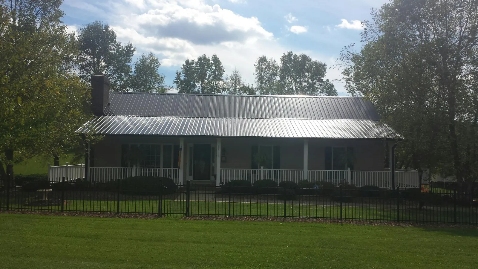 Gray metal roof on a brick ranch with a full width front porch — Gutter Guard Installation work by our crew in Nassau