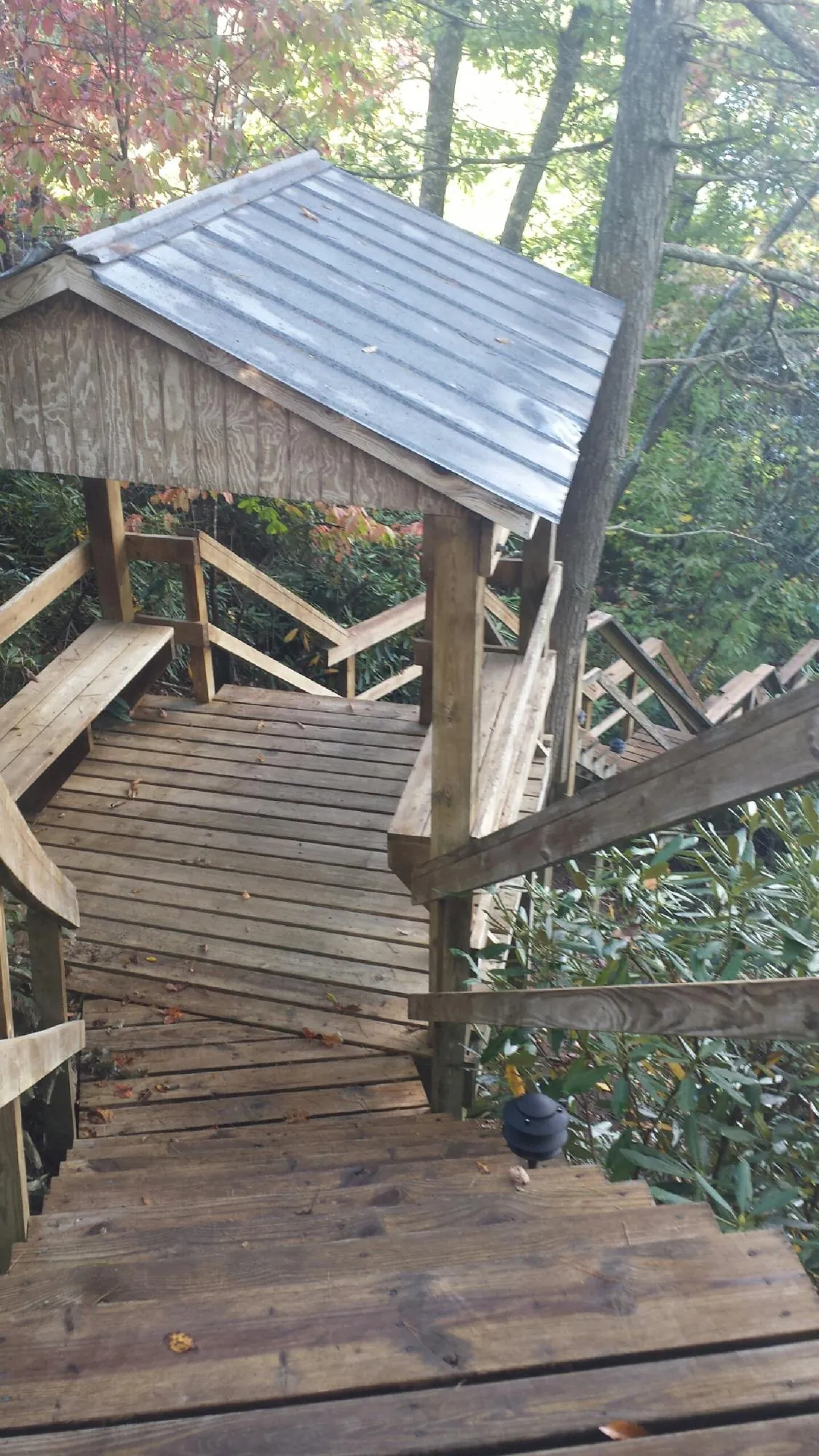 Metal roofed shelter over wooden steps on a wooded walkway — Skylight Repair & Installation work by our crew in Nassau