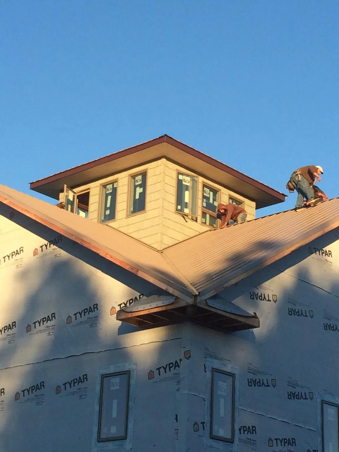 Roofers working around a rooftop cupola on a new metal roof at sunset — Roof Waterproofing in Nassau by Roofing Brothers